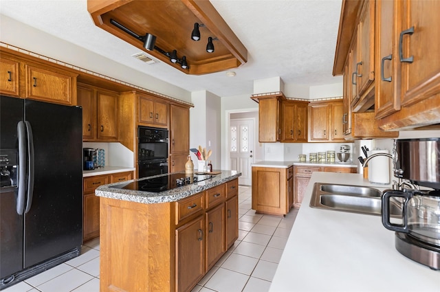 kitchen with brown cabinetry, visible vents, a kitchen island, and black appliances