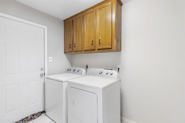 washroom featuring washer and dryer, cabinet space, and light tile patterned floors