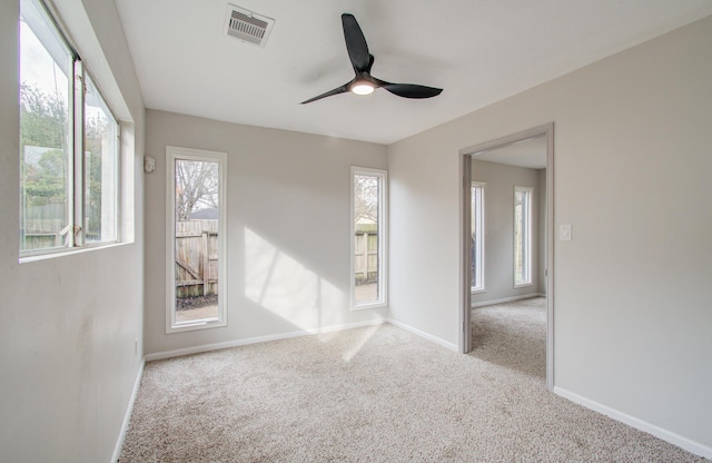 carpeted empty room featuring ceiling fan, visible vents, and baseboards