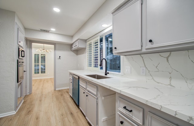 kitchen with a sink, visible vents, appliances with stainless steel finishes, light wood-type flooring, and backsplash