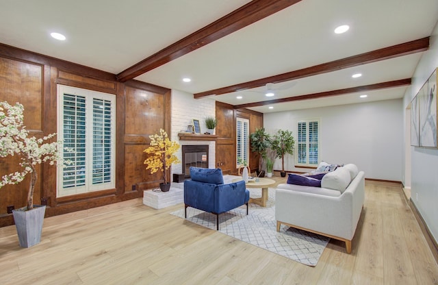 living room featuring beam ceiling, a fireplace, recessed lighting, light wood-style floors, and baseboards