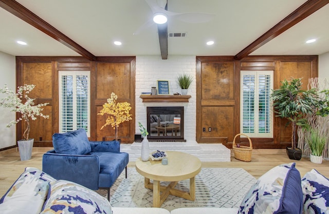 living area with visible vents, beamed ceiling, a fireplace, and wood finished floors