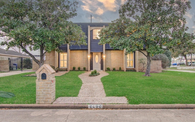 view of front of home with a front lawn, fence, and brick siding