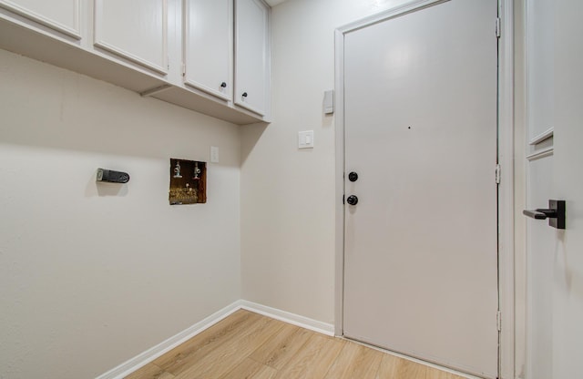 clothes washing area with baseboards, hookup for a washing machine, cabinet space, and light wood-style floors