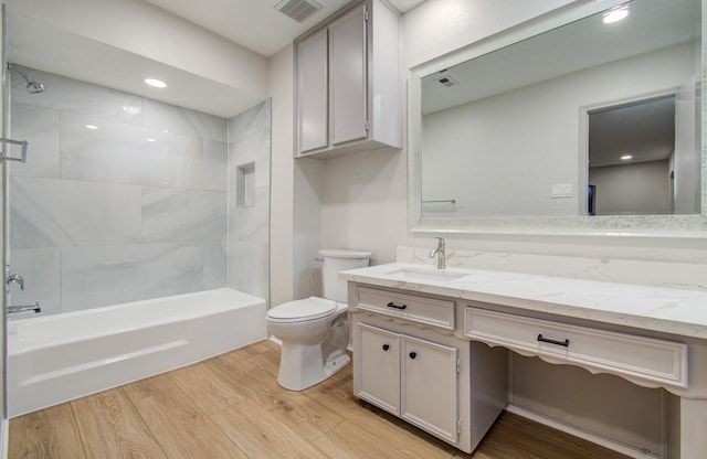 full bath featuring bathtub / shower combination, visible vents, toilet, vanity, and wood finished floors