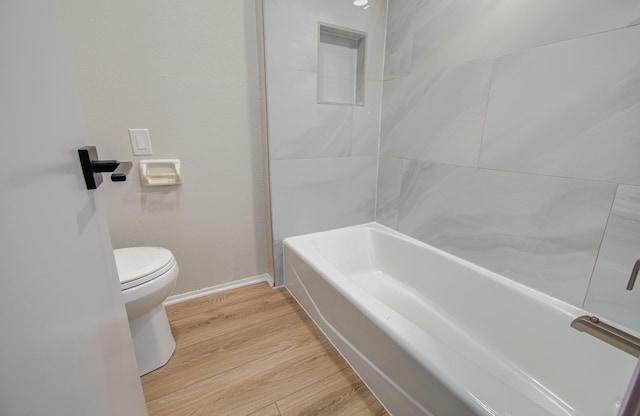 full bath featuring a washtub, toilet, wood finished floors, baseboards, and walk in shower