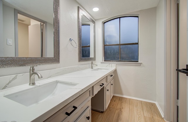 full bath with double vanity, baseboards, a sink, and wood finished floors