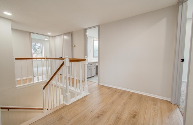 hallway featuring recessed lighting, baseboards, wood finished floors, and an upstairs landing