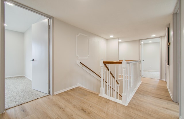 hallway with recessed lighting, baseboards, an upstairs landing, and wood finished floors