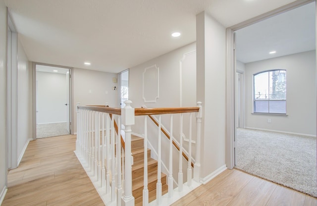 corridor featuring recessed lighting, baseboards, light wood finished floors, and an upstairs landing