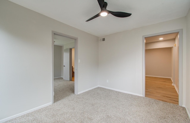 carpeted empty room with ceiling fan, visible vents, and baseboards