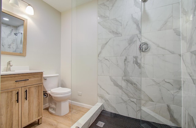 full bathroom with baseboards, vanity, toilet, and a walk in shower