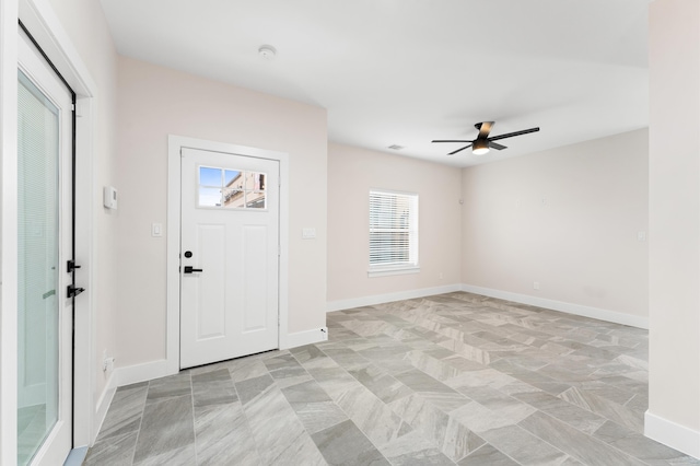 foyer entrance featuring baseboards and a ceiling fan