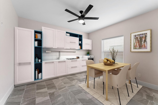 kitchen with baseboards, ceiling fan, light countertops, white cabinetry, and open shelves