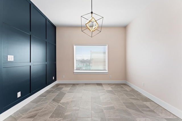 empty room with baseboards and an inviting chandelier