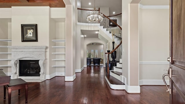 entryway featuring baseboards, arched walkways, hardwood / wood-style floors, stairs, and a high end fireplace