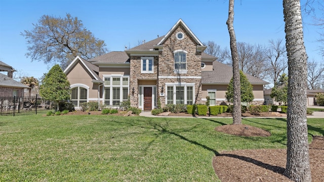 view of front of property with stone siding, a front yard, fence, and stucco siding