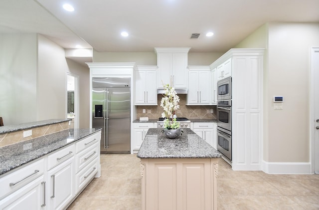 44 Tall Trl, Missouri City, TX 77459 - kitchen with light stone counters, built in appliances, backsplash, white cabinetry, and visible vents