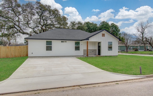 view of front of home featuring board and batten siding, a front yard, driveway, and fence