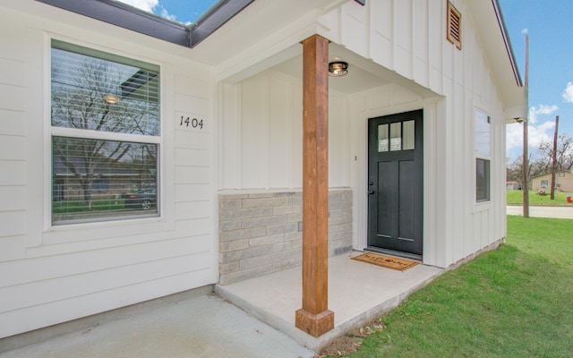 doorway to property featuring a lawn and board and batten siding