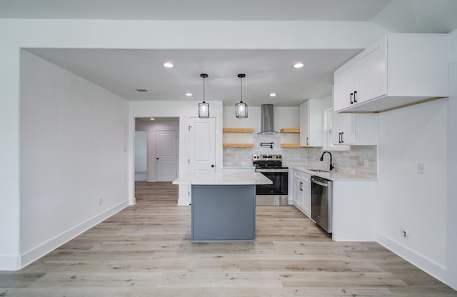 kitchen featuring appliances with stainless steel finishes, a center island, a sink, wall chimney range hood, and backsplash