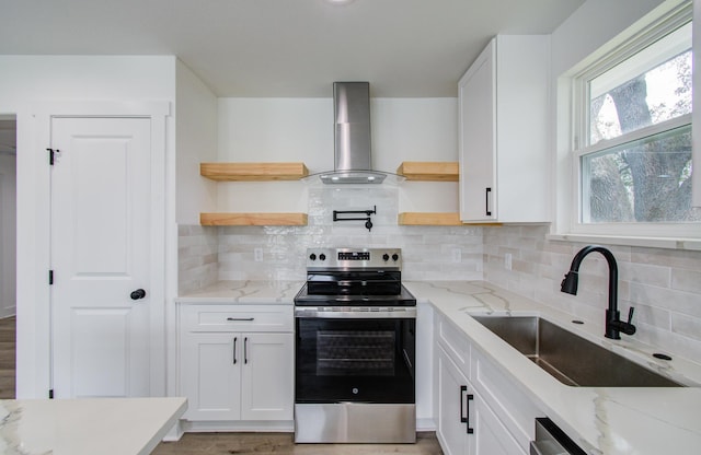 kitchen featuring open shelves, a sink, white cabinetry, stainless steel range with electric cooktop, and wall chimney exhaust hood