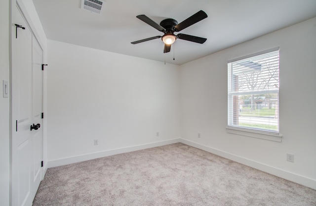 carpeted empty room with visible vents, ceiling fan, and baseboards