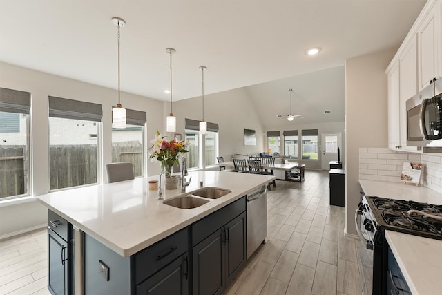 kitchen with wood finish floors, light countertops, appliances with stainless steel finishes, white cabinets, and a sink