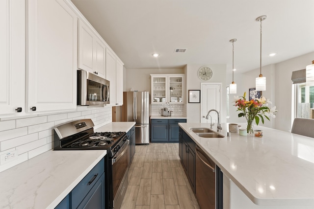 kitchen featuring stainless steel appliances, visible vents, glass insert cabinets, white cabinetry, and a sink