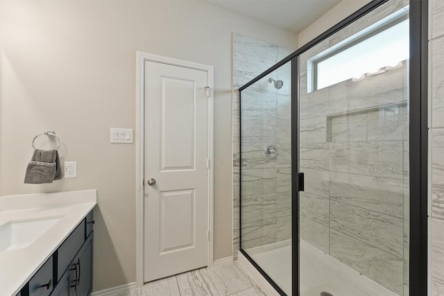 full bathroom featuring marble finish floor, a shower stall, baseboards, and vanity