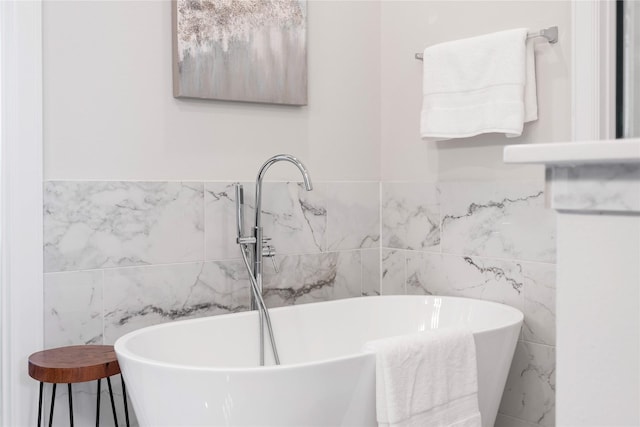 full bath featuring a freestanding tub, a sink, and tile walls