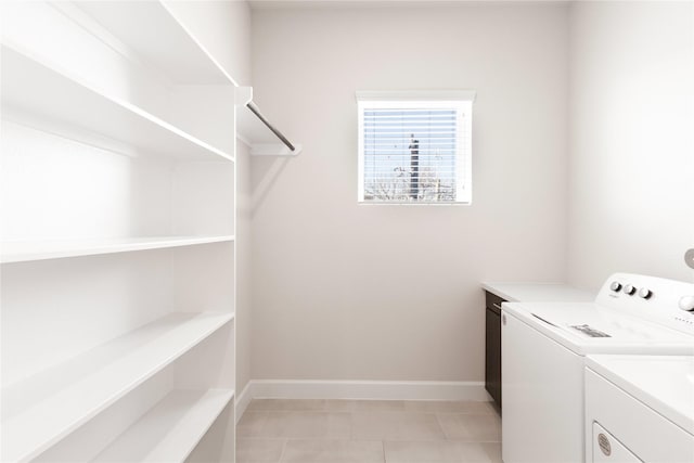 clothes washing area featuring laundry area, baseboards, washing machine and clothes dryer, and light tile patterned floors