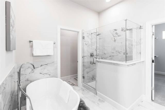 full bath with marble finish floor, a soaking tub, a marble finish shower, and baseboards