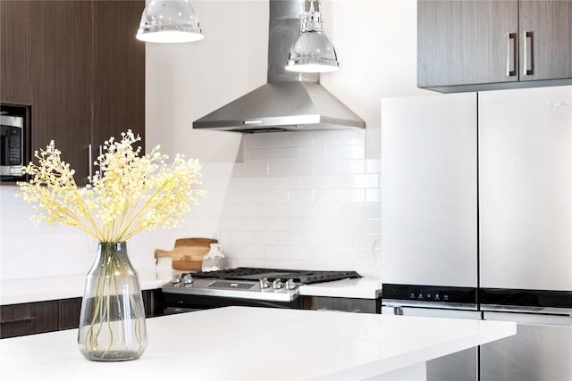 kitchen featuring light countertops, modern cabinets, wall chimney range hood, backsplash, and freestanding refrigerator