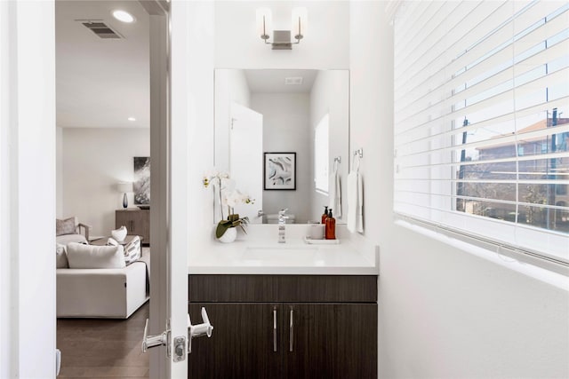 bathroom with recessed lighting, visible vents, vanity, and wood finished floors