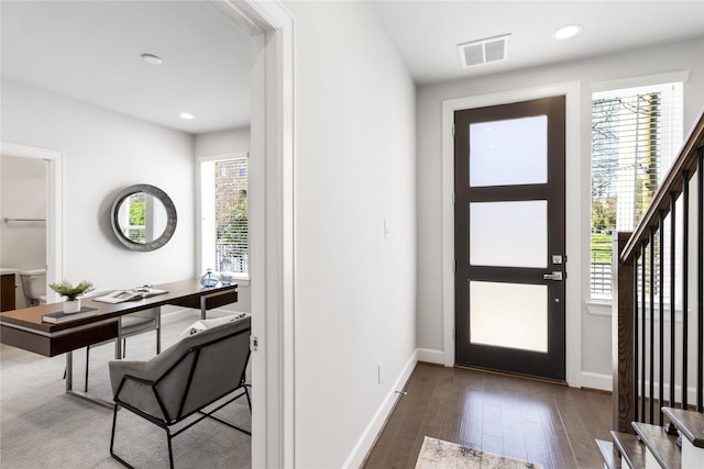 entrance foyer featuring a healthy amount of sunlight, hardwood / wood-style flooring, stairs, and visible vents