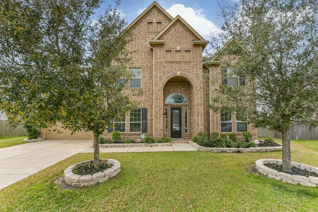 view of front of property featuring brick siding, fence, driveway, and a front lawn