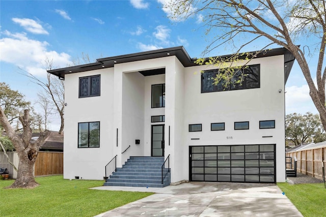 contemporary home with a front yard, fence, driveway, and stucco siding