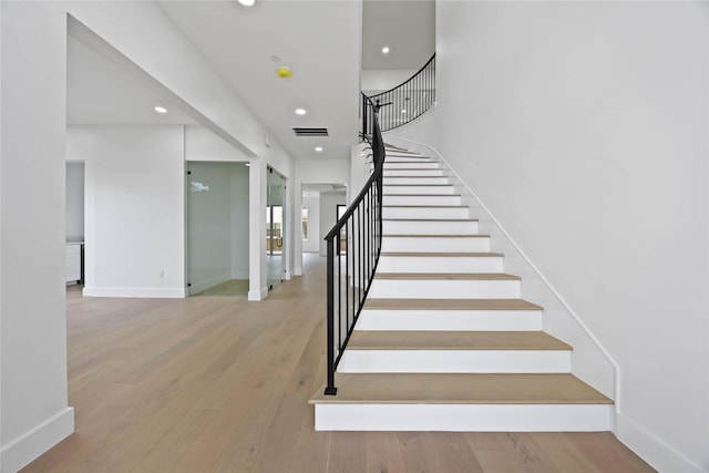 stairway featuring baseboards, visible vents, wood finished floors, and recessed lighting