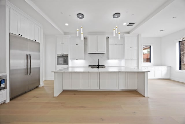 kitchen with light wood-style flooring, stainless steel appliances, visible vents, white cabinetry, and a large island with sink