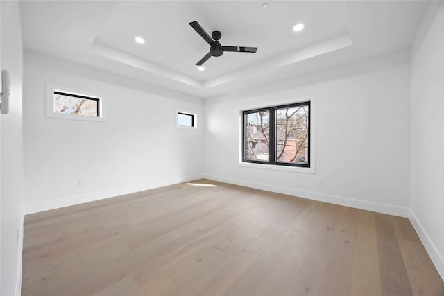 spare room with recessed lighting, a raised ceiling, wood-type flooring, ceiling fan, and baseboards