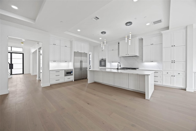 kitchen with stainless steel appliances, light wood-type flooring, a raised ceiling, and visible vents