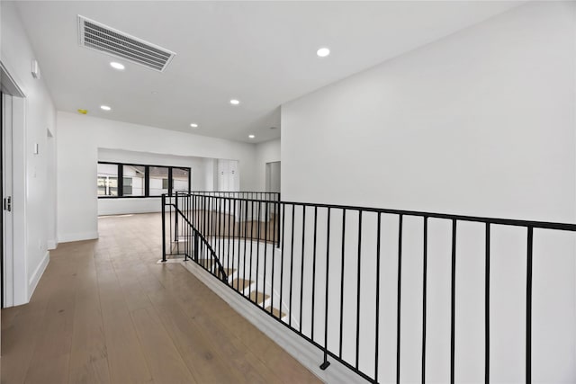 hall featuring recessed lighting, visible vents, an upstairs landing, wood finished floors, and baseboards