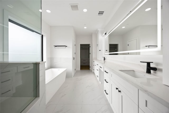 bathroom with visible vents, marble finish floor, a freestanding bath, a sink, and recessed lighting