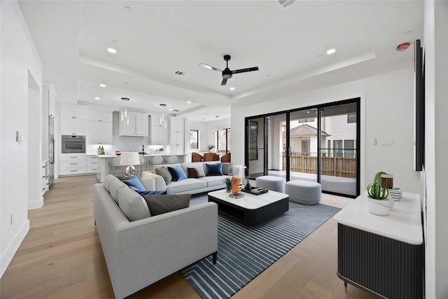 living room featuring light wood-style floors, a tray ceiling, and recessed lighting