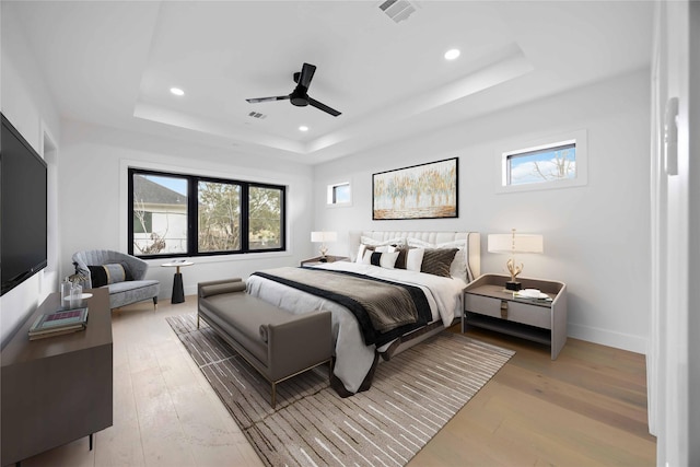 bedroom featuring a tray ceiling, recessed lighting, visible vents, and light wood-style floors