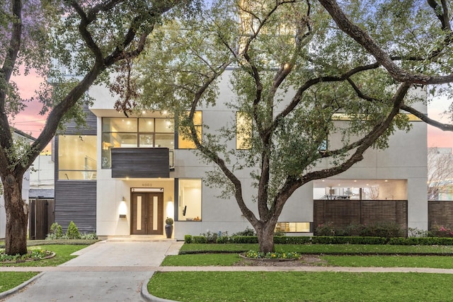 view of front of property with stucco siding, fence, and a yard