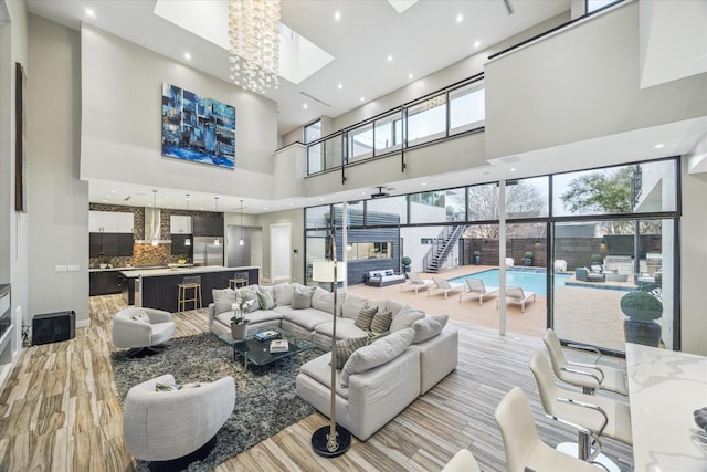 living room featuring light wood-type flooring, a skylight, and a high ceiling