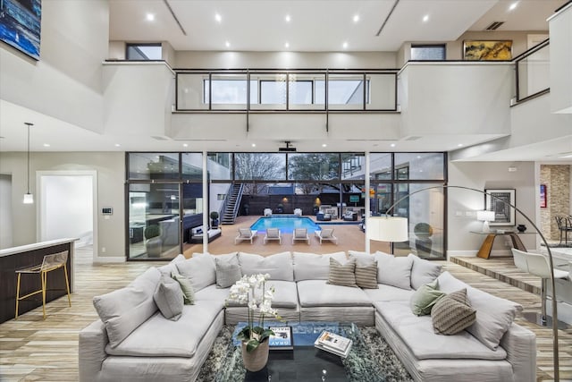 sunken living room with a towering ceiling, light wood-style floors, baseboards, and visible vents