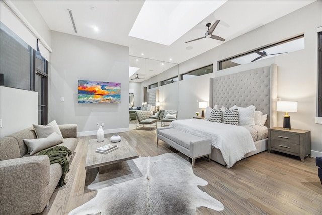 bedroom with light wood-style floors, a skylight, visible vents, and baseboards